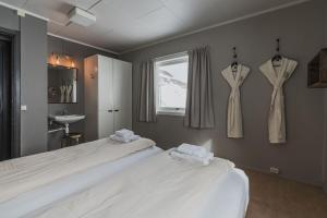 朗伊尔城煤矿工小屋旅舍的卧室配有两张床和挂在墙上的两件连衣裙