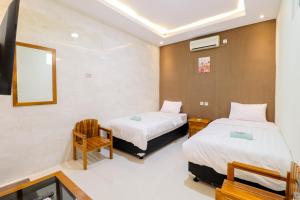 日惹Hotel Safara Yogyakarta的酒店客房,配有两张床和椅子