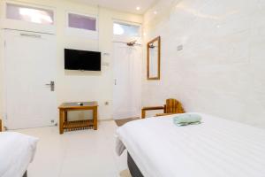 日惹Hotel Safara Yogyakarta的一间卧室设有两张床,墙上配有电视。