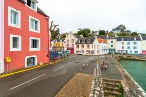 索宗Le Sauzon - Vue sur le port - Proche de la plage的一条城市街道,在水边有色彩缤纷的建筑