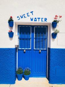 CarratracaSweet Water Caminito del Rey的一座建筑,上面有蓝色的门和盆栽植物