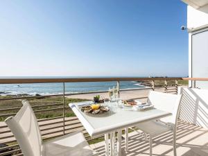 基伯龙Sofitel Quiberon Thalassa sea & spa的海滩阳台的白色桌椅