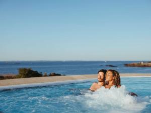 基伯龙Sofitel Quiberon Thalassa sea & spa的坐在游泳池里的男人和女人
