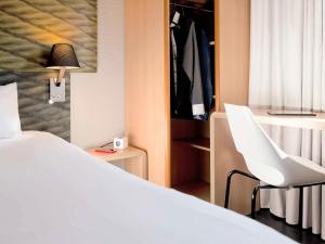 萨莱切Ibis Hôtel Sallanches的卧室配有白色的床和白色椅子