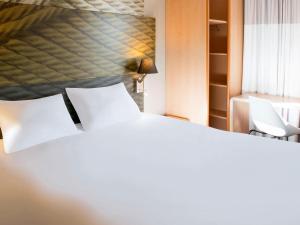 萨莱切Ibis Hôtel Sallanches的卧室配有白色的床和2把白色椅子