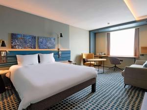 卢森堡卢森堡基希贝格诺富特酒店的酒店客房带一张大床和一把椅子