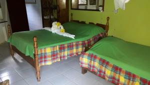 Marigot芙蓉谷酒店 的两张带绿床单的床和一只填充动物