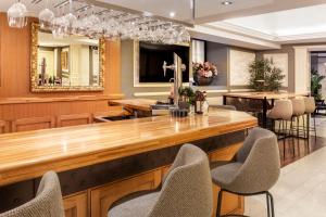 马德里加泰罗尼亚科尔特斯酒店的餐厅设有酒吧,配有椅子和镜子