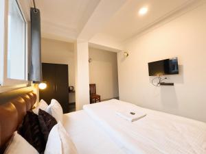 甘托克Hotel Sherabling的卧室配有白色的床,墙上配有电视