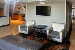 橘园Quality Inn Southside Jacksonville的客厅配有两把椅子和墙上的电视