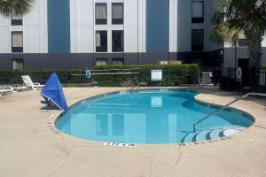 橘园Quality Inn Southside Jacksonville的大楼前带蓝伞的大型游泳池