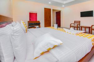 钦奈FabHotel Krishna Residency的卧室配有一张带椅子的白色大床