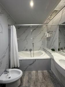 阿斯塔纳PORT INN Hotel的白色的浴室设有浴缸和水槽。