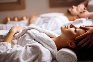 海若克利欧Ethereal White Resort Hotel & Spa的男人和女人躺在床上毛巾下
