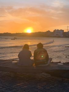 厄尔梅达诺Los Martines el Medano的两个人坐在长凳上看日落