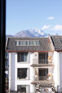 丽江La Maison du Laoshay Lijiang的一座白色的建筑,设有阳台,享有山脉的背景