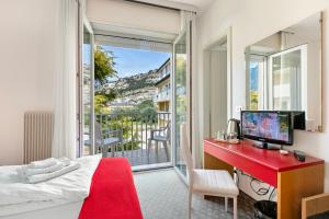 托尔博莱Bike & Wind Hotel Villa Maria - Happy Rentals的一间卧室配有一张床和一张红色的书桌,设有一个阳台