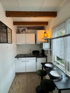 诺德韦克Hello Noordwijk - Tiny House Dahliastraat 60的厨房配有白色橱柜和桌椅