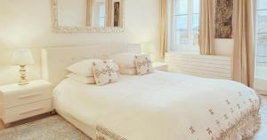 波朗特吕阿雪依Spa酒店的白色的卧室配有白色的床和镜子