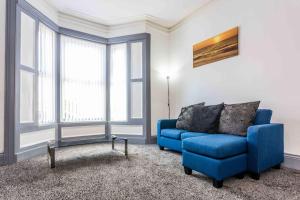 桑德兰Guest Homes - Bambro Flat的客厅设有蓝色的沙发和窗户。