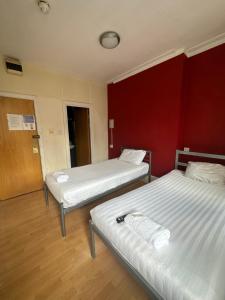 伦敦伯克利苑酒店 的红色墙壁的客房内的两张床
