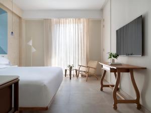 圣多明各Kimpton Las Mercedes, an IHG Hotel的一间卧室配有一张床、一张书桌和一台电视。