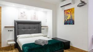马拉加Ilustre Rooms by Beehive Vacances的一间卧室配有一张大床和绿色的搁脚凳