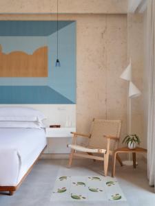 圣多明各Kimpton Las Mercedes, an IHG Hotel的一间卧室配有一张床和一把椅子
