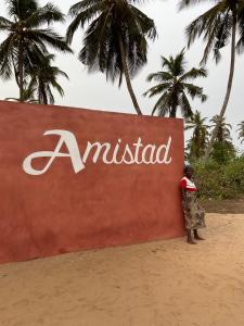 OuidahAmistad的站在海滩上标志前面的女人
