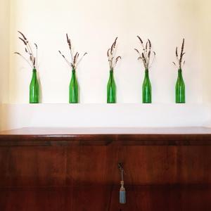 BorghettoVilla Montefiore Country Resort的搁架上的四个绿瓶
