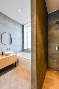 奥斯特韦克12, Luxe Designer Oase - Historisch Centrum - Uitzicht的一间带水槽、浴缸和镜子的浴室