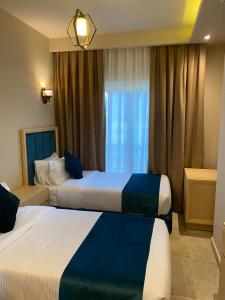 阿莱曼Coast Hotel的酒店客房设有两张床和窗户。