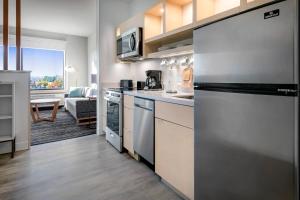 伦瑟姆TownePlace Suites By Marriott Wrentham Plainville的一间带不锈钢冰箱的厨房和一间客厅