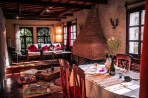 危地马拉安地瓜Baraka Antigua的一间带桌子和砖砌壁炉的用餐室