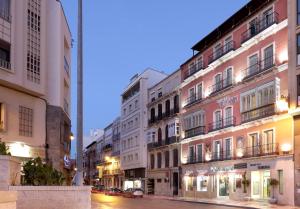 马拉加Sercotel Tribuna Málaga的夜幕降临的城市街道上的一排建筑物