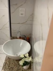 阿拉沙Phos Hostel的浴室设有白色水槽和花朵,位于柜台上