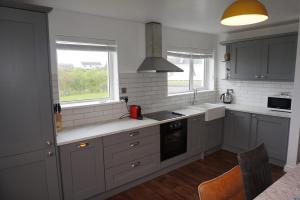 巴利巴宁18 Ballybunion Holiday Cottages的厨房配有白色橱柜、水槽和窗户。