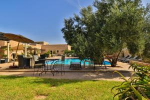 索维拉Essaouira Lodge的一个带桌椅的庭院和一个游泳池