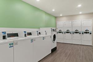 迈尔斯堡WoodSpring Suites Fort Myers - Cape Coral的洗衣房配有白色洗衣机和洗衣机