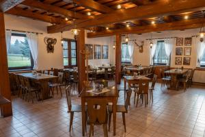 Dolní BečvaKoliba Pod Horů的餐厅设有木桌、椅子和窗户。