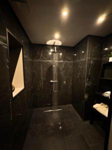 Flémalle-GrandeLes bulles d'or的浴室设有黑色瓷砖墙和淋浴。