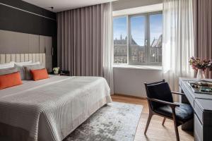 阿姆斯特丹Anantara Grand Hotel Krasnapolsky Amsterdam的一间卧室配有一张床和一张桌子及椅子