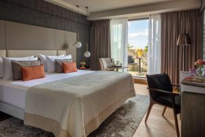阿姆斯特丹Anantara Grand Hotel Krasnapolsky Amsterdam的一间卧室配有一张床、一张书桌和一个窗户。
