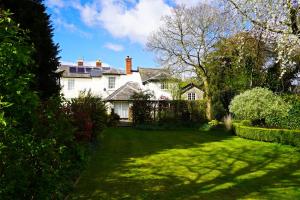 North LydburyThe Old Vicarage self-contained apartments的前面有绿色草坪的白色房子