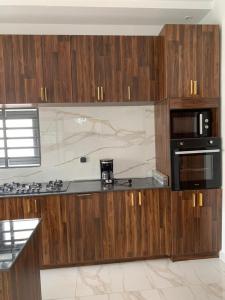 科托努Luxe Dandji的厨房配有木制橱柜、炉灶和微波炉。