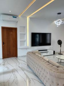 科托努Luxe Dandji的客厅配有大沙发和平面电视