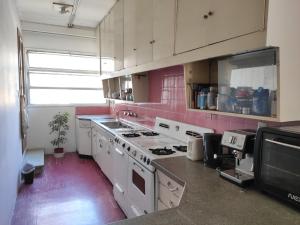 门多萨Habitaciones con baño compartido en Departamento Mid Century Modern的设有带白色家电和粉红色墙壁的厨房