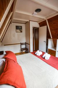 圣马丁德洛斯Apart Hotel Ensueño的一间卧室配有一张带红色床单的大床和椅子