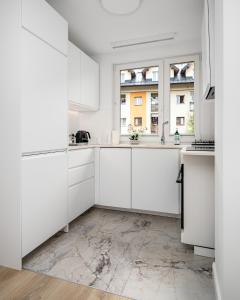 什恰夫尼察Szczawnica Art的白色的厨房配有白色橱柜和窗户