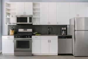 芝加哥Sonder The Plymouth的厨房配有白色橱柜和不锈钢冰箱